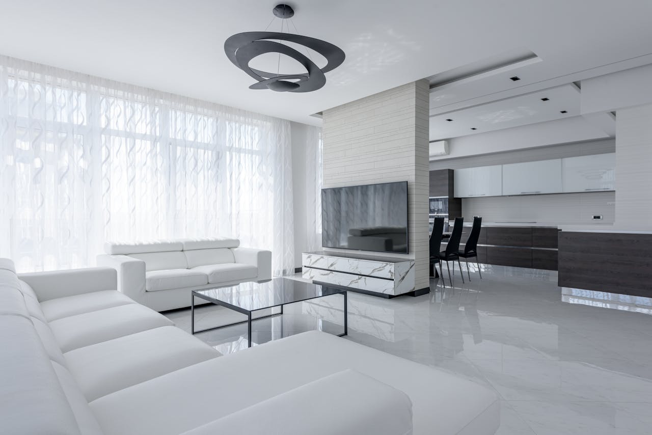 bright-modern-house-interior-with-furniture-6238614 Interior of light apartment with table and couch near TV with cabinet and white walls near window with curtains and stool near lamp