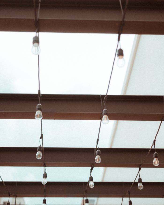 low-angle-view-of-ceiling-structure-and-lamps-5308476 Minimalist ceiling design featuring beams and hanging light bulbs, perfect for architecture inspiration.
