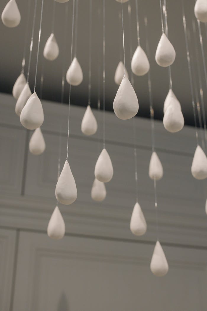 Close-up view of white raindrop-shaped decorations hanging from the ceiling indoors.